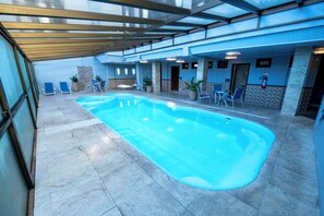 An indoor swimming pool with lounge chairs and potted plants. - Hotel Serra Nevada (Canela)
