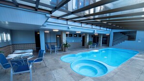 An indoor swimming pool with blue water, surrounded by blue chairs and tables. - Hotel Serra Nevada (Canela)