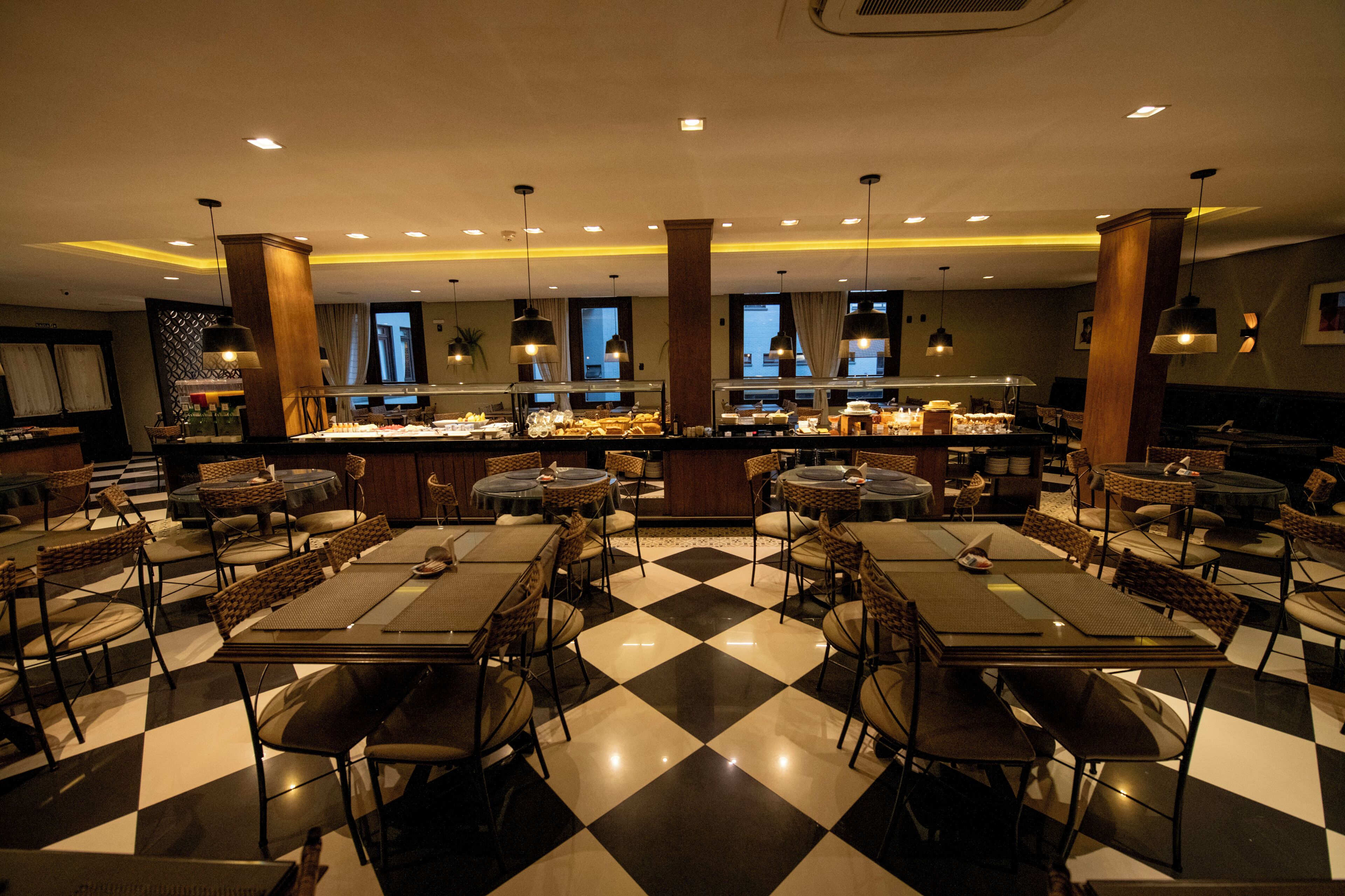 A restaurant with checkered flooring, multiple dining tables, and chairs.