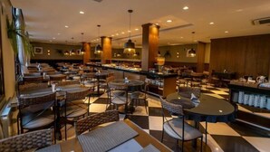 A spacious restaurant with multiple tables and chairs, a bar area, and pendant lighting. - Hotel Serra Nevada (Canela)