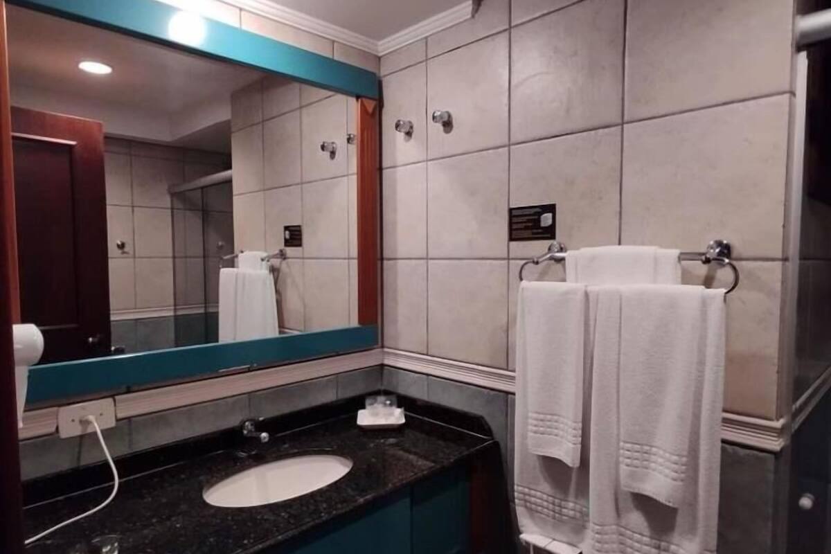 Un baño moderno con un espejo grande, un lavabo y una zona de ducha.