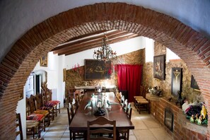 Un comedor con una mesa de madera larga, sillas y una lámpara de araña.