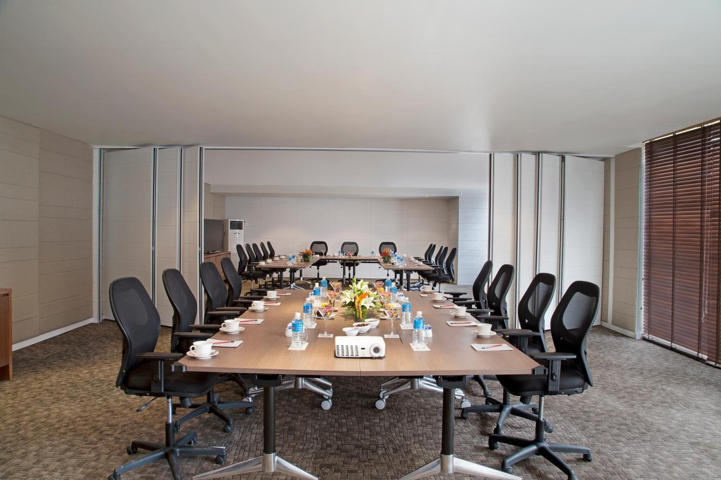 A conference room with a long table, multiple chairs, water bottles, and a projector.