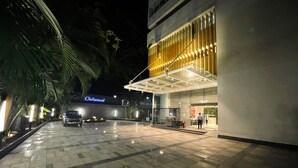 A hotel entrance with a tiled pavement, a parked van, and a building with a modern design and a sign that reads "Oakwood".