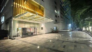 A hotel entrance with a modern design, featuring a glass facade and a wooden panel accent.