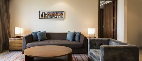 A modern hotel room with a sofa, a round coffee table, and two lamps.