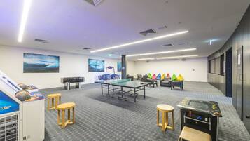 Una habitación con mesas de ping pong, taburetes y una mesa para tenis de mesa.