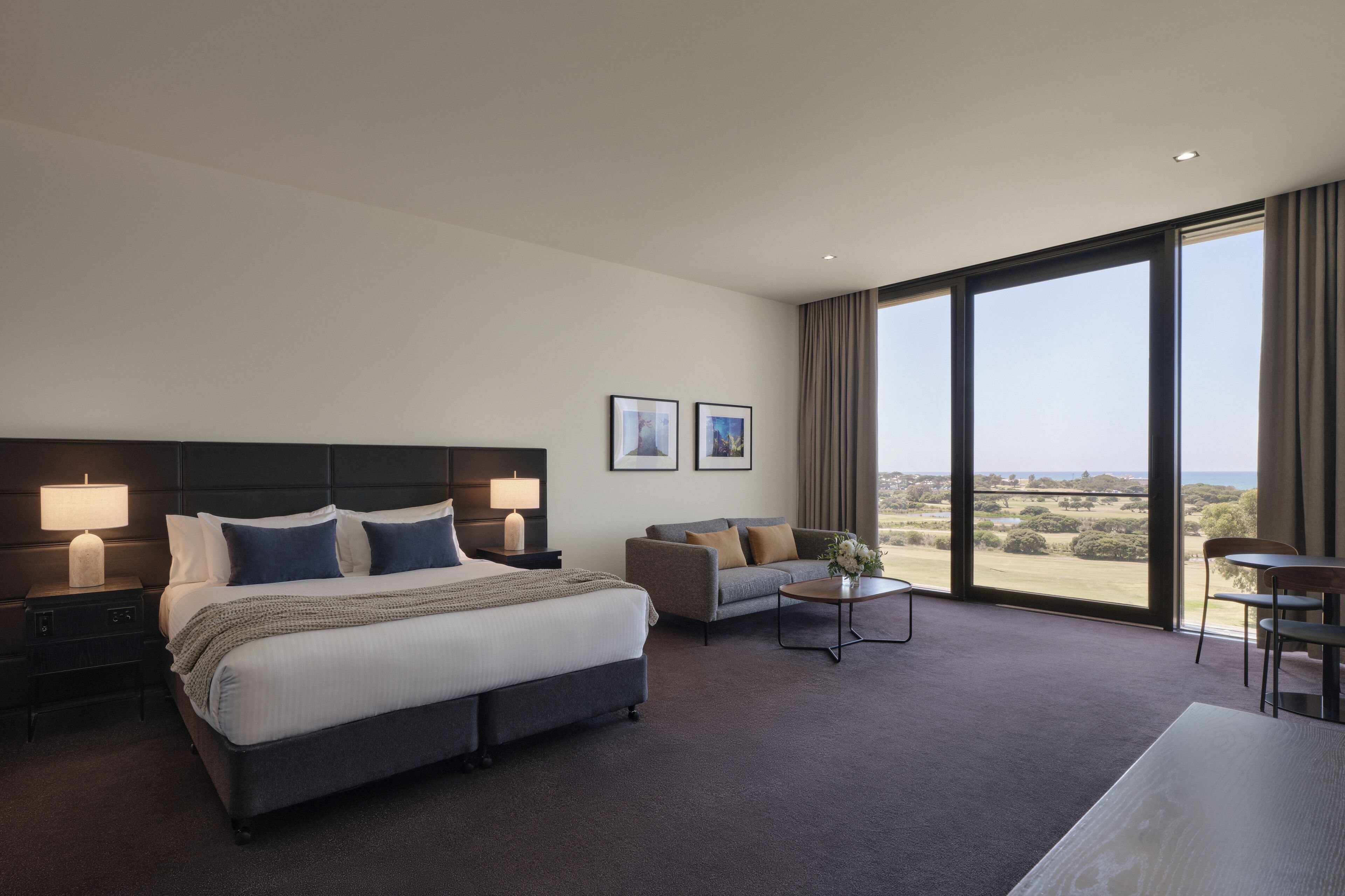 Une chambre d’hôtel moderne dotée d’un grand lit, d’un canapé, d’une petite table et offrant une vue sur la campagne.