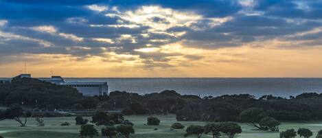 Um campo de golfe com um lago, árvores e um edifício ao fundo.