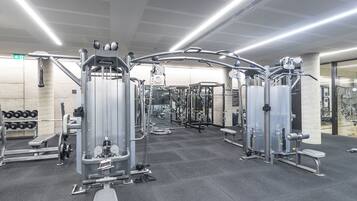 A gym with various exercise machines, benches, and dumbbells.