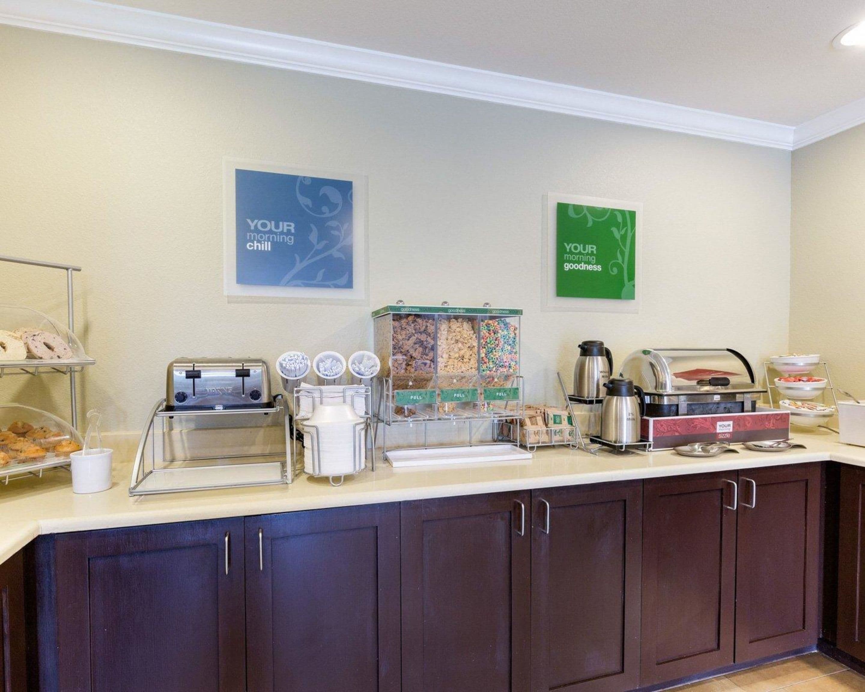 A breakfast bar with a coffee machine, tea station, and various food containers.
