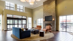 A spacious lobby with a large seating area, a stone accent wall, a flat-screen TV, and large windows. - Comfort Suites near Westchase on Beltway 8 (Houston)