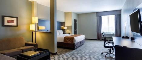 A hotel room with a bed, a desk, a chair, a sofa, a small table, and a TV.