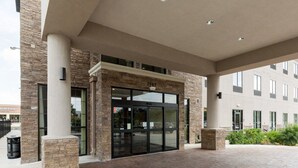 A building entrance with a stone facade, large glass doors, and a paved walkway. - Comfort Suites near Westchase on Beltway 8 (Houston)