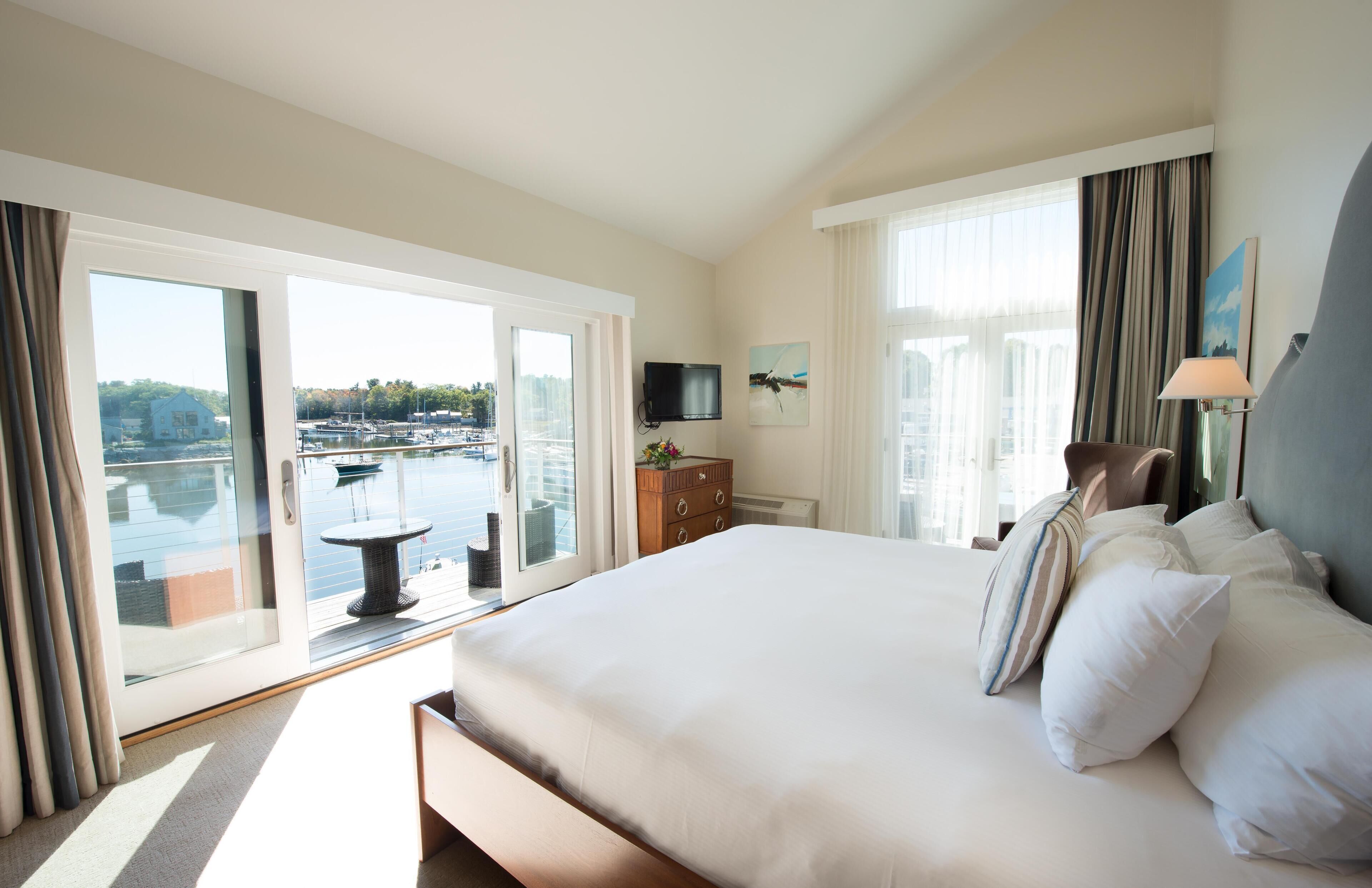 Ein Hotelzimmer mit einem großen Bett, einem Fernseher, einem Schreibtisch und Blick auf den Yachthafen.