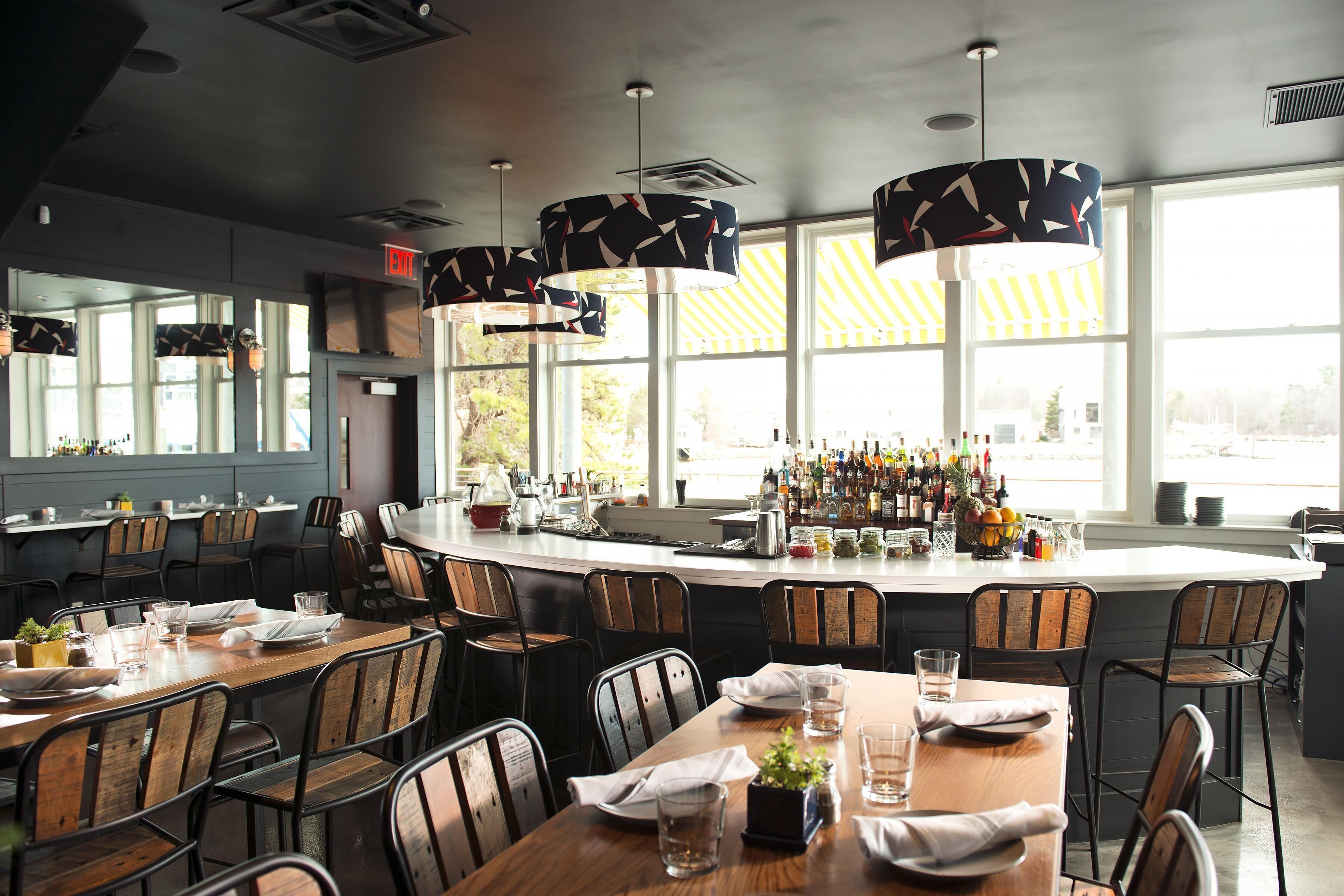 A restaurant with a bar area, wooden tables, and chairs.