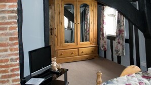 A bedroom with a wooden wardrobe, a television on a small table, and a bed with a floral bedspread. - Woodview Bed & Breakfast (Colchester)