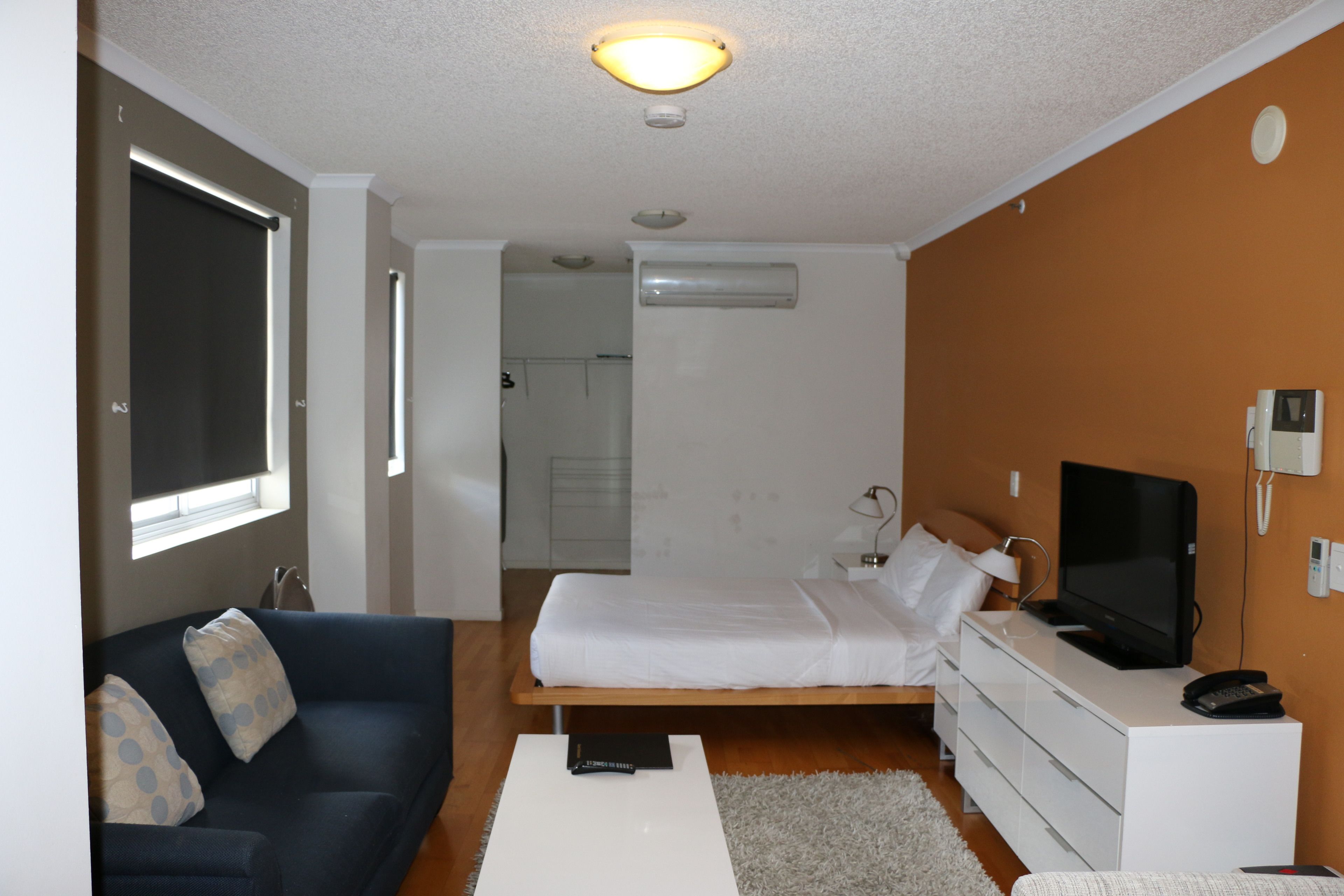 Ein modernes Hotelzimmer mit Bett, Sofa, Fernseher und Schreibtisch.