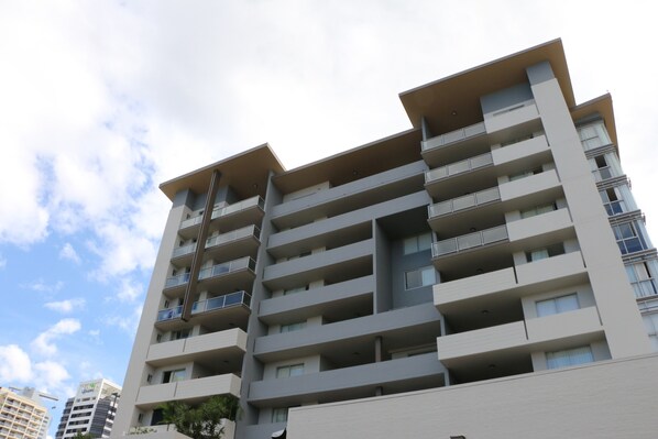 Un edificio residencial de varios pisos con balcones, ventanas grandes y techo plano.
