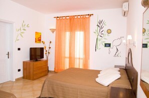 A bedroom with a bed, a TV on a wooden dresser, a window with orange curtains, and wall art. - Vistamare Bed and Breakfast (Alliste)