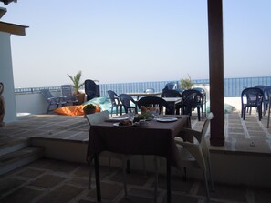 A terrace with a table set for dining, chairs, and a view of the sea. - Vistamare Bed and Breakfast (Alliste)