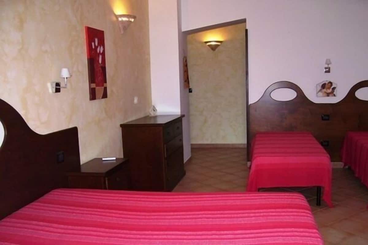Habitación de hotel con cama, escritorio y silla. Cuenta con dos mesitas de noche y una lámpara de pared.