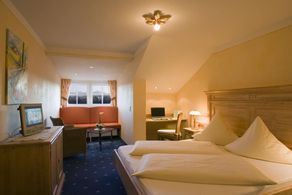 Une chambre d’hôtel équipée d’un lit, d’un bureau, d’une chaise, d’une télévision et d’une fenêtre avec des rideaux.