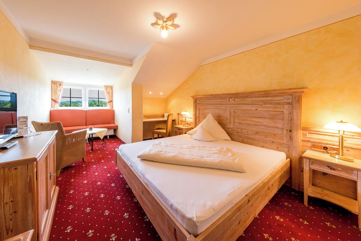 Une chambre d’hôtel équipée d’un lit, d’un bureau, d’une chaise, d’une télévision et d’une fenêtre avec des rideaux.