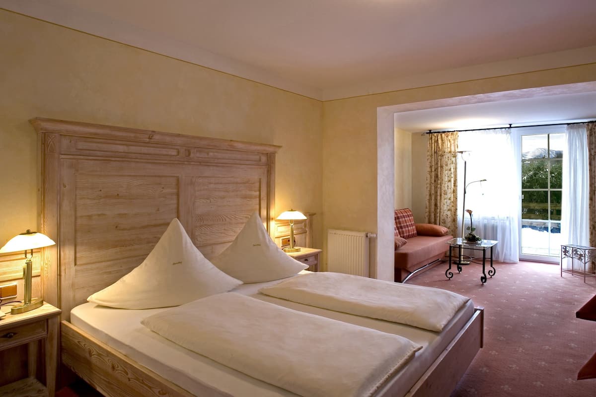 Une chambre d’hôtel avec un grand lit, deux lampes de chevet, une petite table, une chaise et une vue sur l’extérieur par une fenêtre.