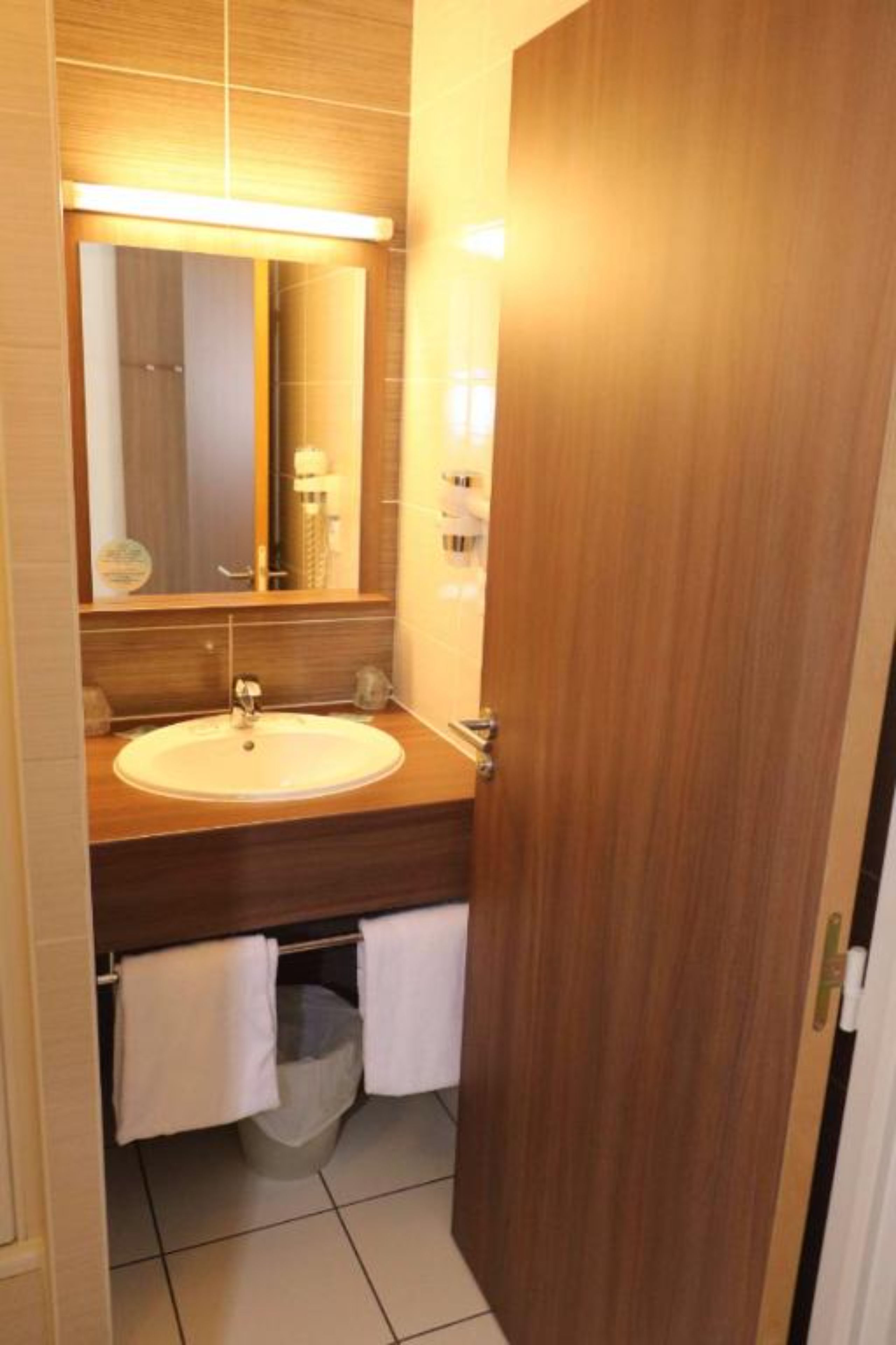 A bathroom with a wooden vanity, a sink, a mirror, and a towel rack.