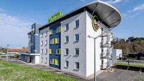 Ein modernes Hotel mit gewölbter Dachform, mehreren Etagen und dem gut sichtbaren B&B Hotels Logo.