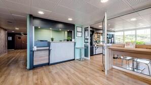 Ein moderner Empfangsbereich mit Holzboden, einer Rezeption und einer Glastrennwand.