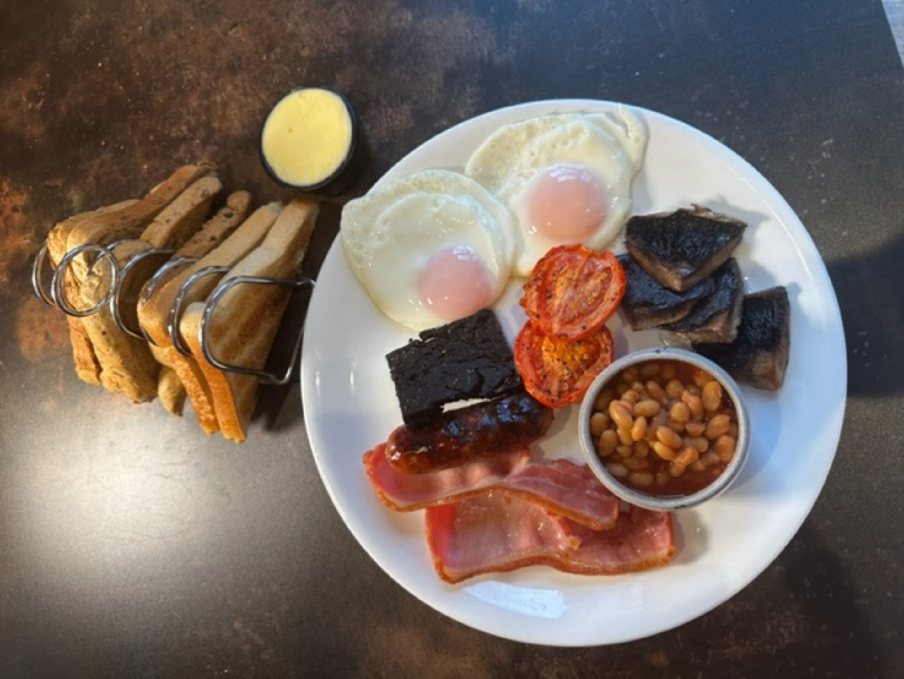 A plate with eggs, bacon, beans, tomatoes, and toast.