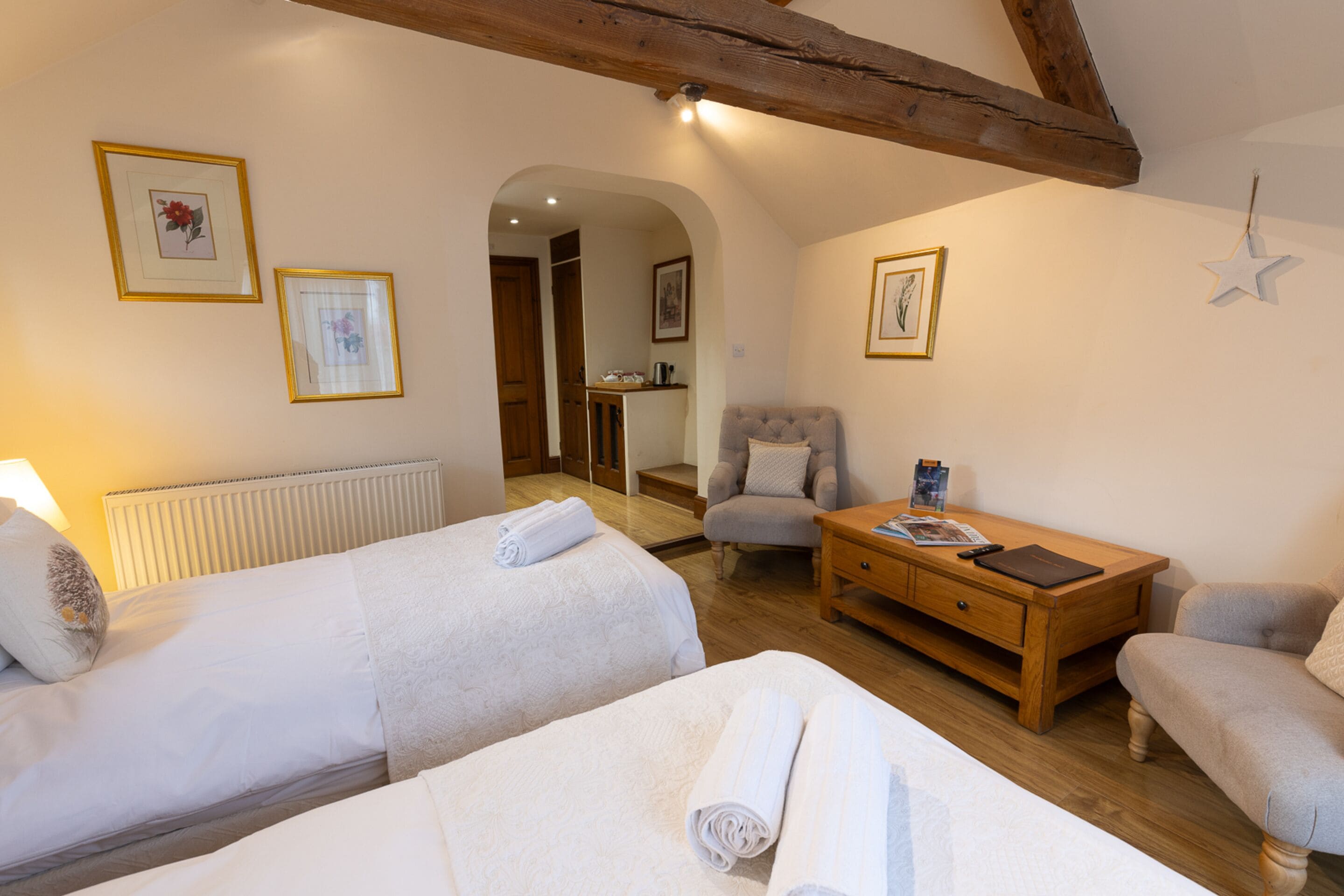Una habitación acogedora con dos camas, una mesita de madera, una silla y una decoración con estrellas en la pared.