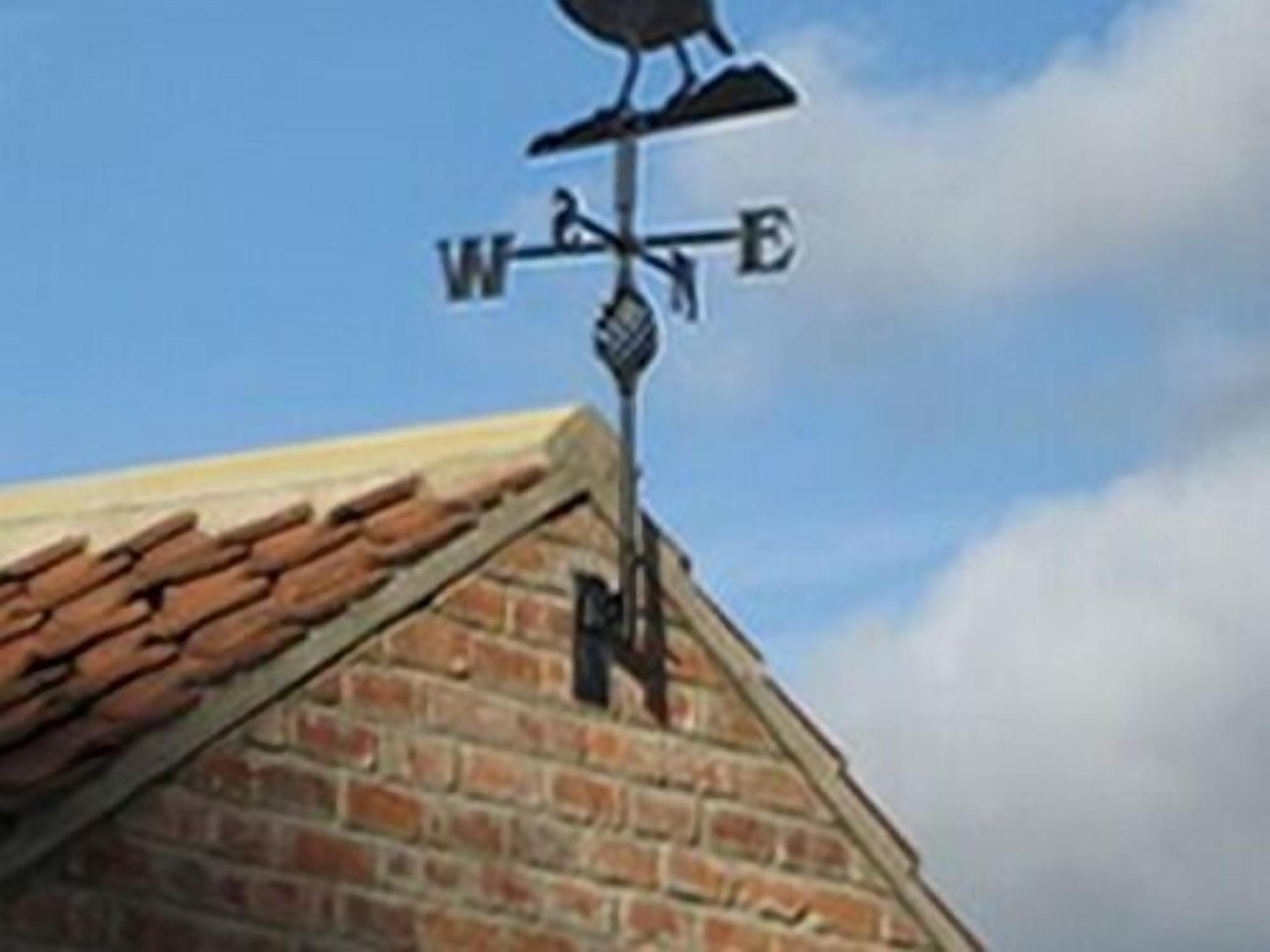 A weather vane on a brick building.