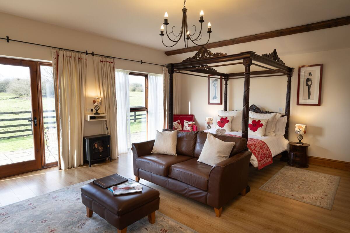 Quarto com cama de dossel, sofá e lareira.