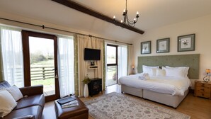 A bedroom with a large bed, a sofa, a TV, and a view of the outdoors.