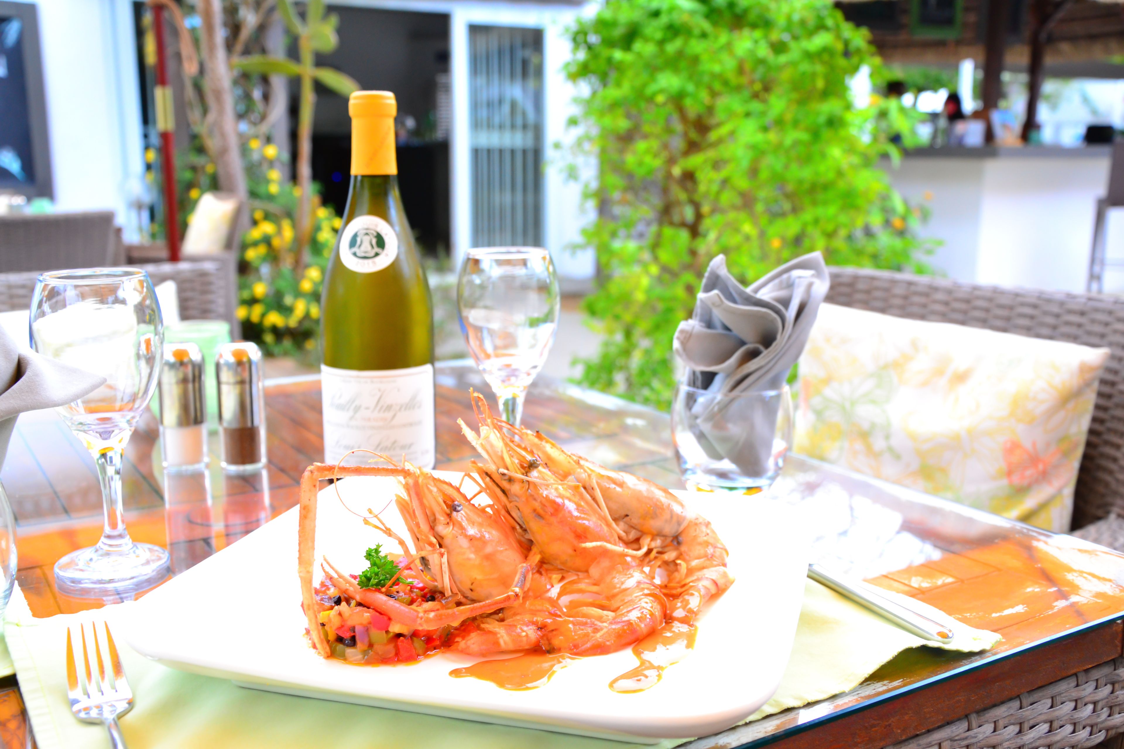 A dining table with a plate of shrimp, a bottle of wine, and glasses.