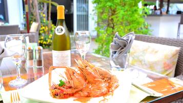 A dining table with a plate of shrimp, a bottle of wine, and glasses.