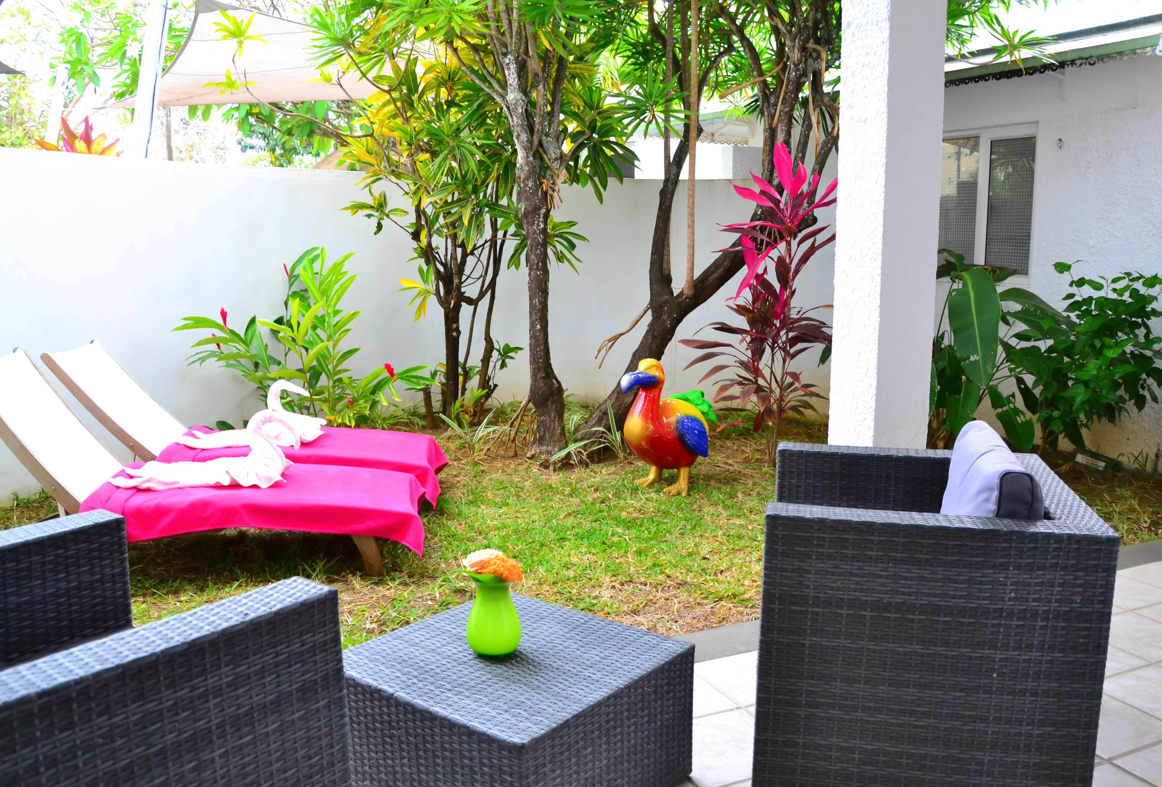 A patio with wicker furniture, a pink tablecloth, and a colorful rooster statue.