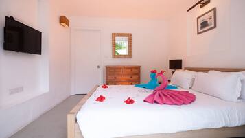 Una camera da letto con un letto, una TV a parete, una cassettiera in legno e uno specchio.