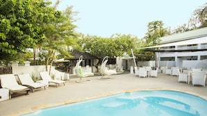 A pool area with lounge chairs and a thatched-roof structure.