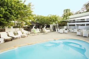 Una piscina al aire libre, sombrillas, sillones reclinables de piscina
