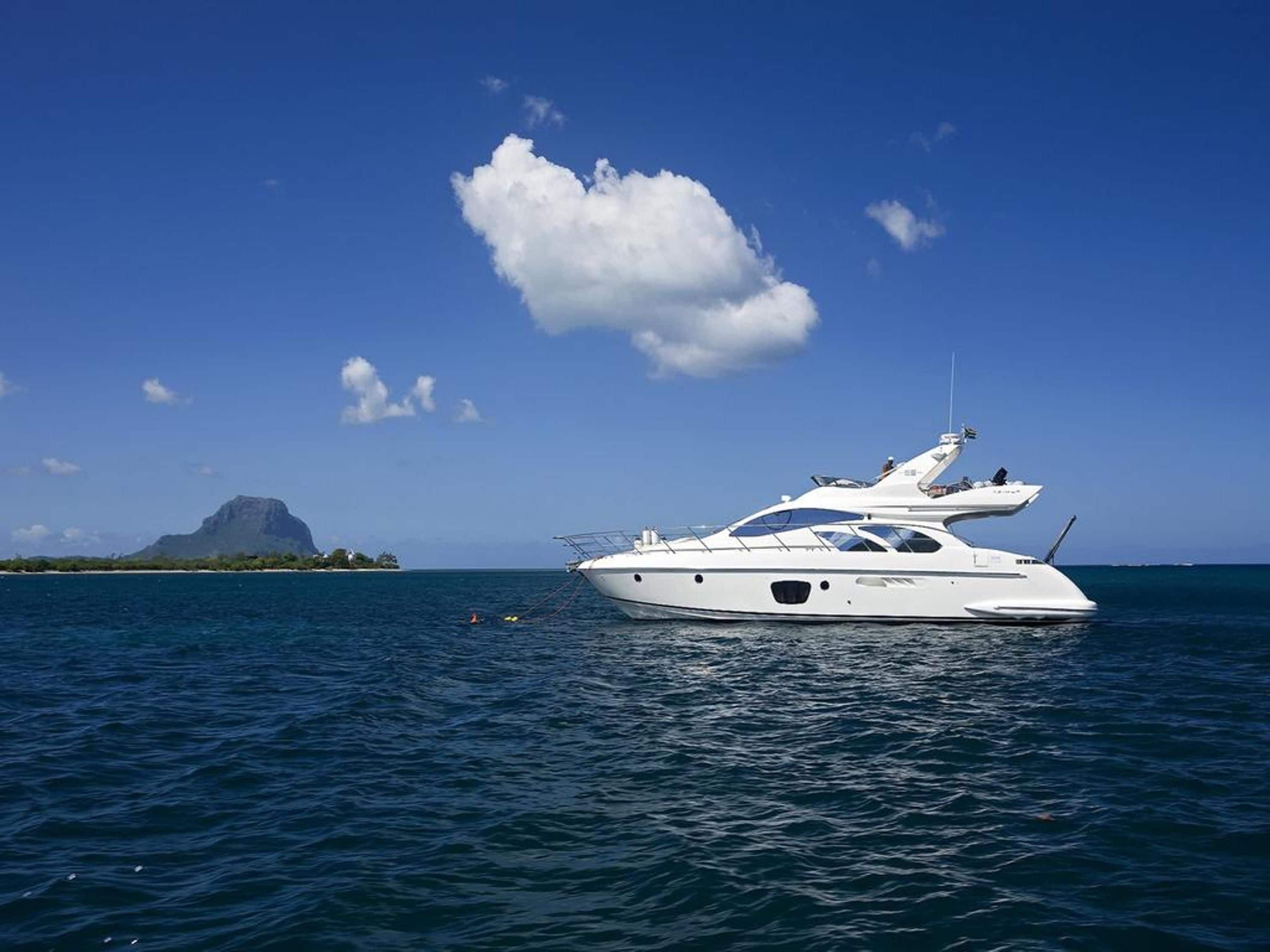 A white yacht on calm waters with a clear blue sky and a distant island.