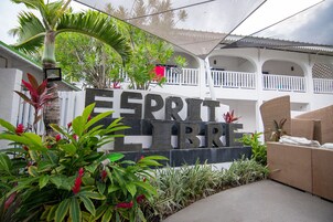 Un letrero que dice 'ESPRIT LIBRE', con un edificio blanco y un área de esparcimiento al aire libre de fondo.