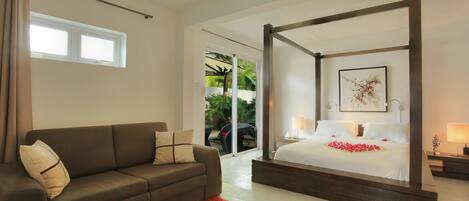 A modern bedroom with a four-poster bed, a sofa, and a red rug.