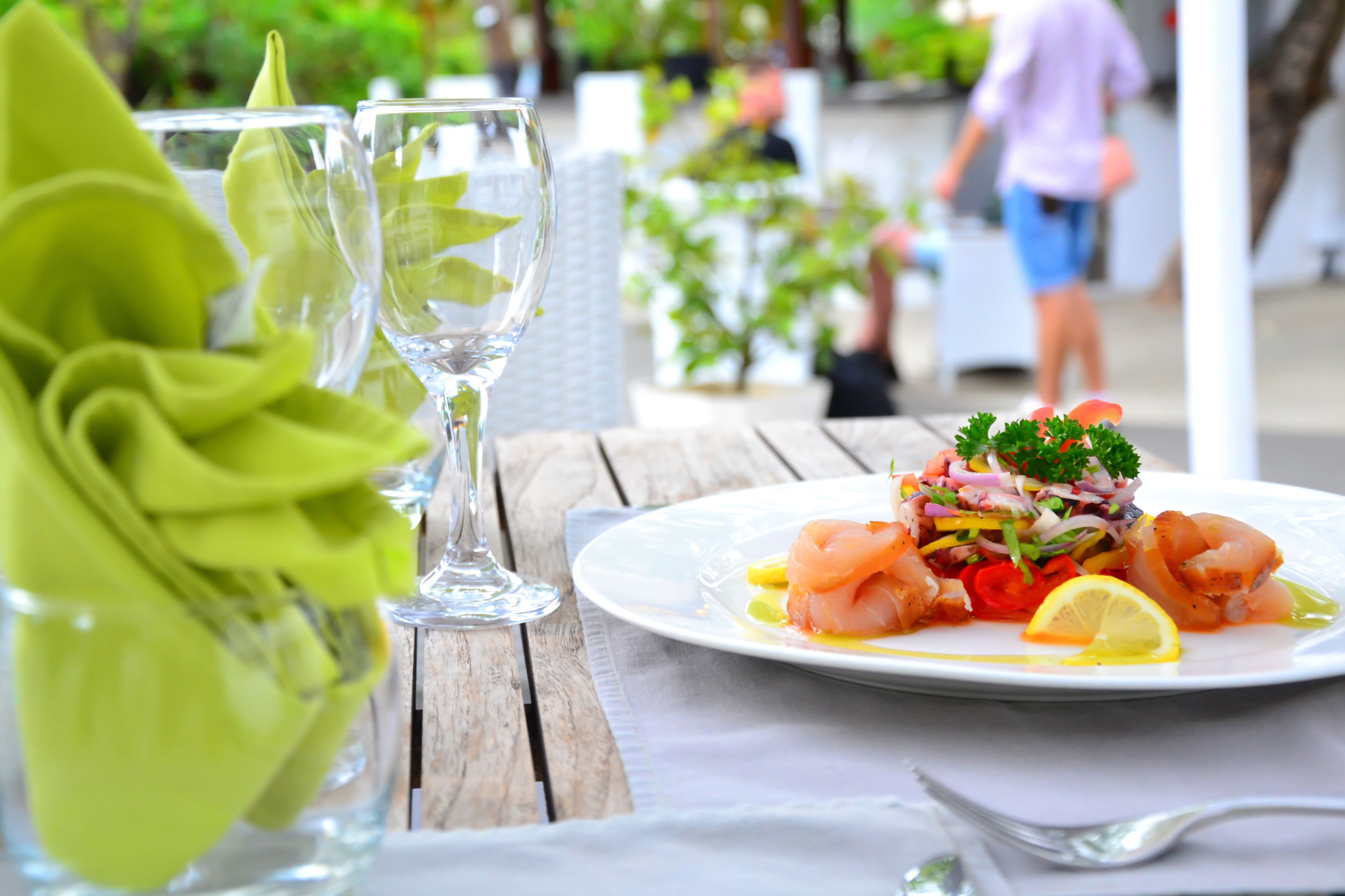 A table with a plate of food, two glasses, and a green napkin.