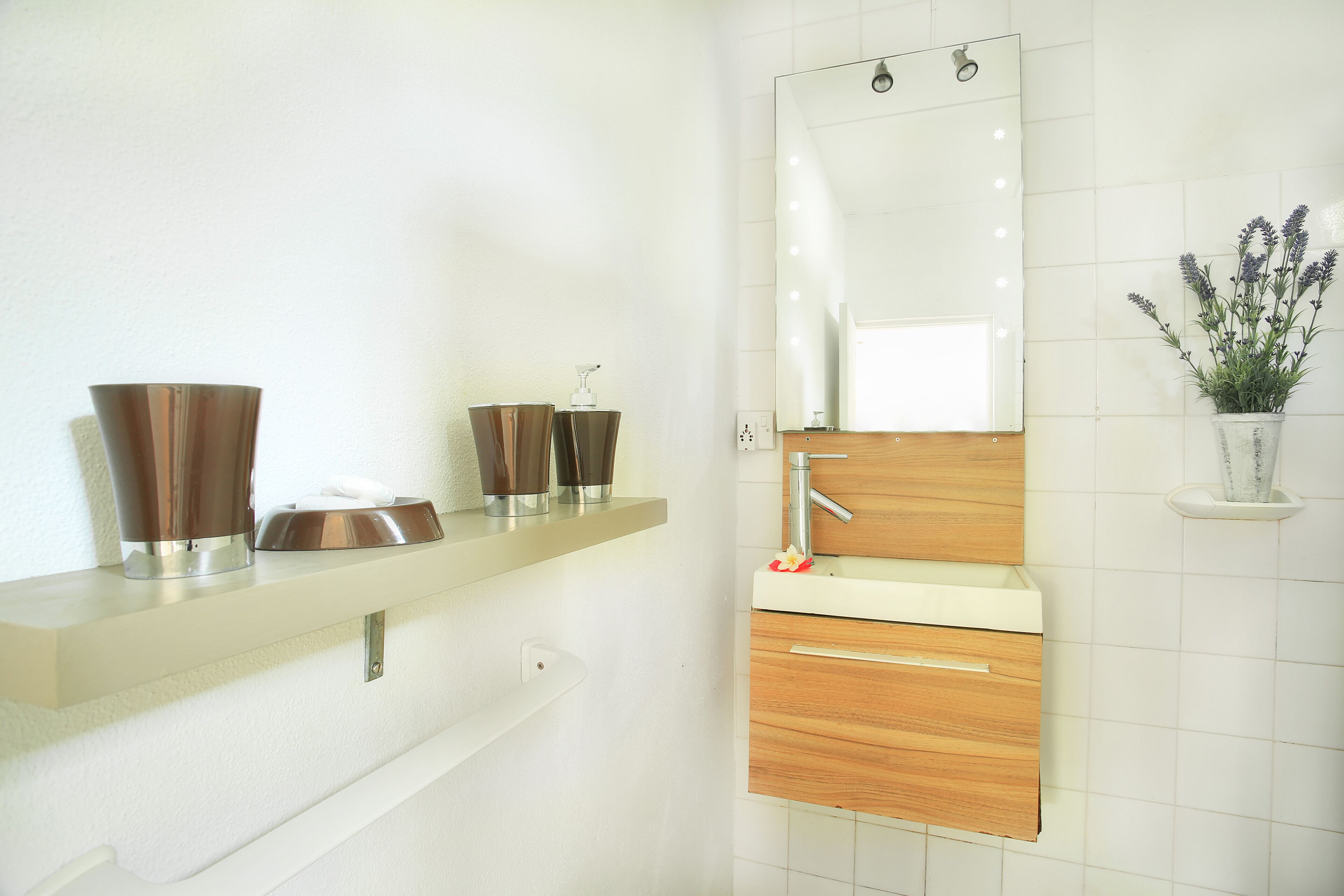 Un bagno moderno con un mobile lavabo bianco, uno specchio e una pianta in vaso.