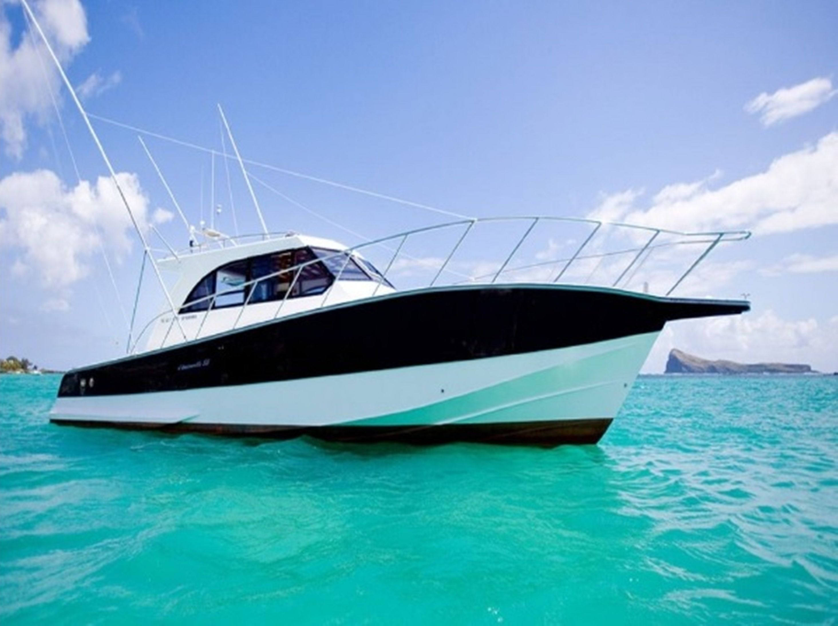 A boat with a cabin and a covered area, floating on turquoise water.