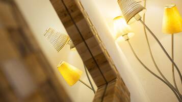 A wall with a mirror and three floor lamps with different shades of yellow.